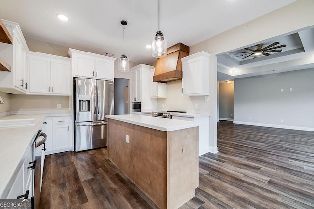 kitchen featuring white cabinetry, custom range hood, appliances with stainless steel finishes, and a tray ceiling