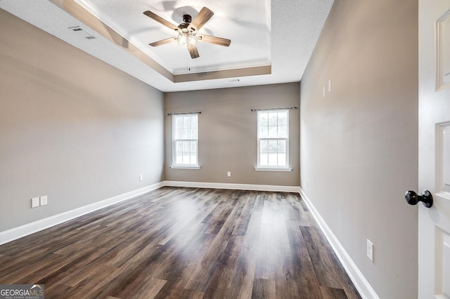 unfurnished room with ceiling fan, a raised ceiling, dark hardwood / wood-style flooring, crown molding, and a textured ceiling