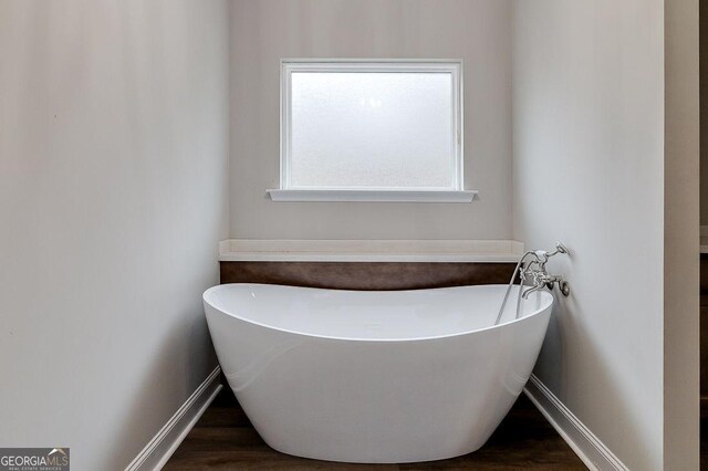 bathroom with a washtub and wood-type flooring