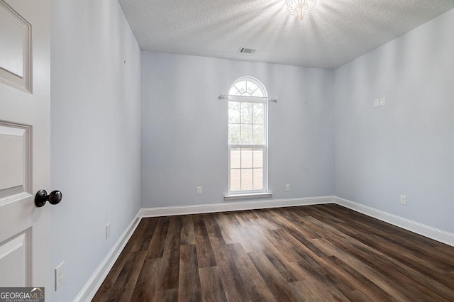 spare room featuring a textured ceiling, a wealth of natural light, and dark wood-type flooring