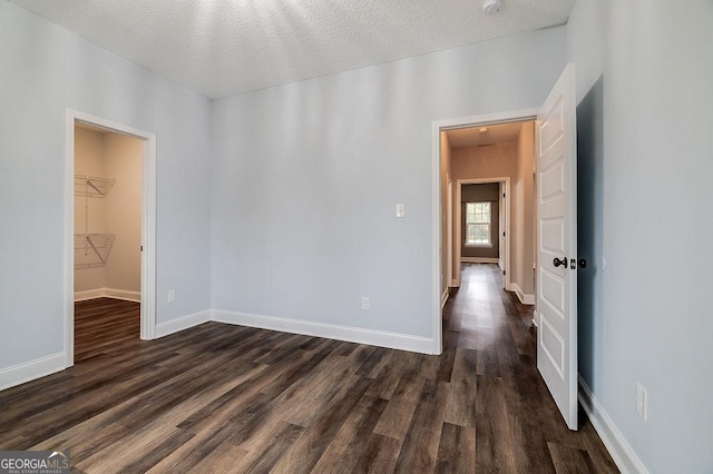 unfurnished room with a textured ceiling and dark hardwood / wood-style flooring