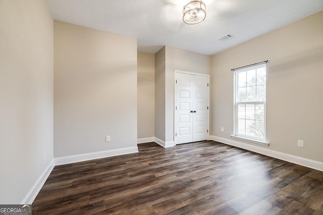 unfurnished bedroom featuring a textured ceiling, a closet, and dark wood-type flooring