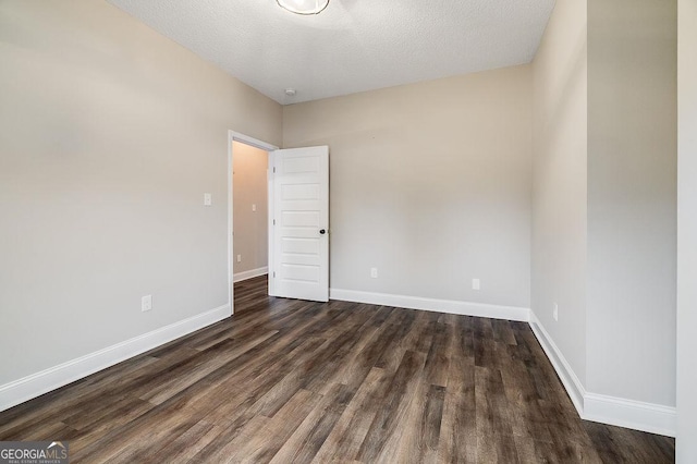 unfurnished room featuring a textured ceiling and dark hardwood / wood-style floors