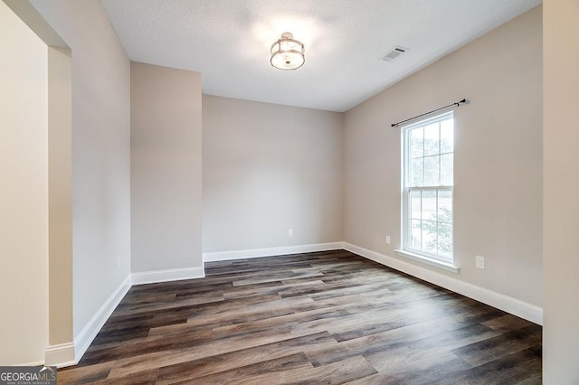 unfurnished room with dark hardwood / wood-style floors and a textured ceiling