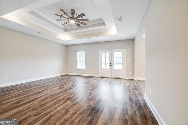 unfurnished room with a tray ceiling, ceiling fan, french doors, and dark wood-type flooring