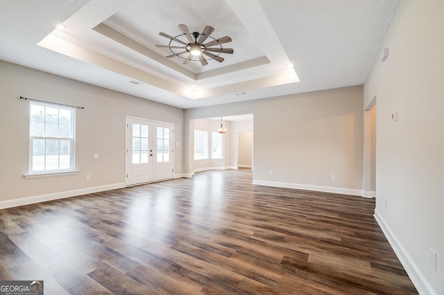 unfurnished room featuring ornamental molding, ceiling fan with notable chandelier, a raised ceiling, and dark wood-type flooring