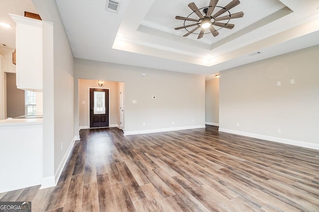 unfurnished living room featuring a tray ceiling, ceiling fan, ornamental molding, and hardwood / wood-style flooring