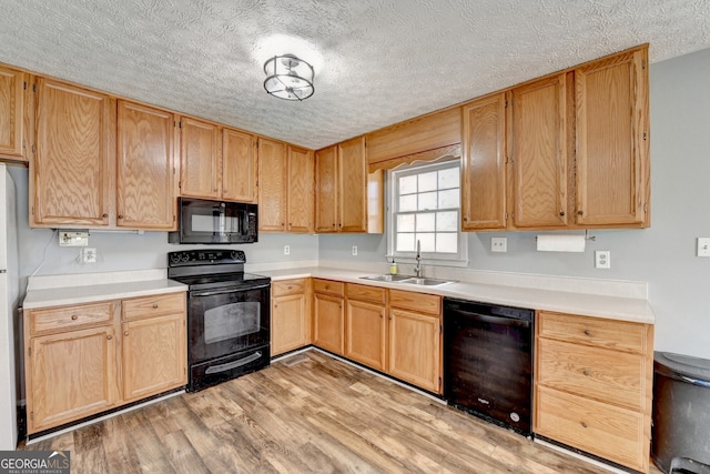 kitchen with a textured ceiling, sink, light hardwood / wood-style flooring, and black appliances