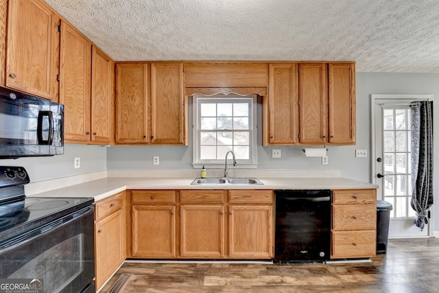 kitchen with a textured ceiling, sink, dark hardwood / wood-style floors, and black appliances