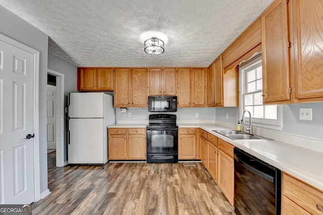 kitchen with a textured ceiling, sink, light hardwood / wood-style floors, and black appliances