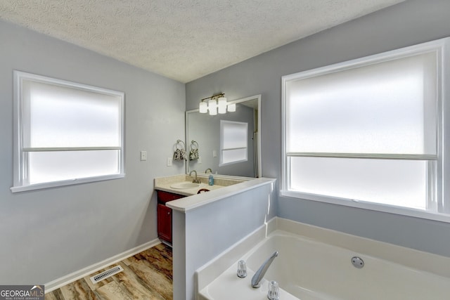 bathroom featuring hardwood / wood-style floors, vanity, a textured ceiling, and a tub