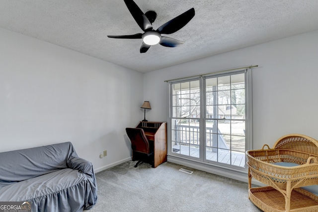 sitting room with a textured ceiling, ceiling fan, and light carpet