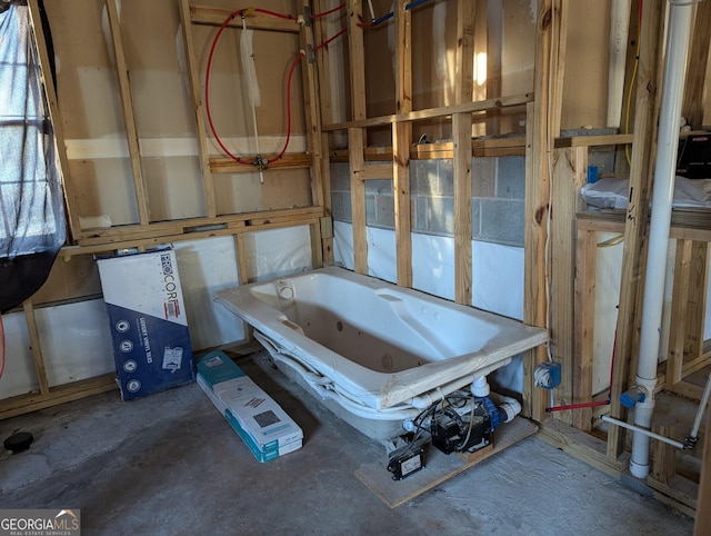 bathroom with a washtub and concrete flooring