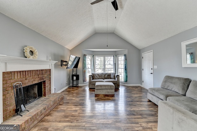 living room featuring a textured ceiling, a brick fireplace, ceiling fan, and dark wood-type flooring