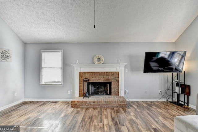 unfurnished living room featuring vaulted ceiling, a fireplace, a textured ceiling, and hardwood / wood-style flooring