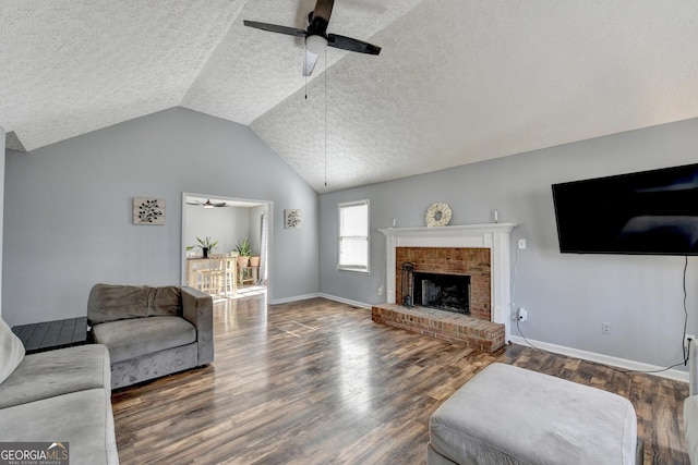 living room with vaulted ceiling, a brick fireplace, ceiling fan, and dark wood-type flooring