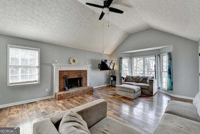 living room with ceiling fan, wood-type flooring, lofted ceiling, and a brick fireplace