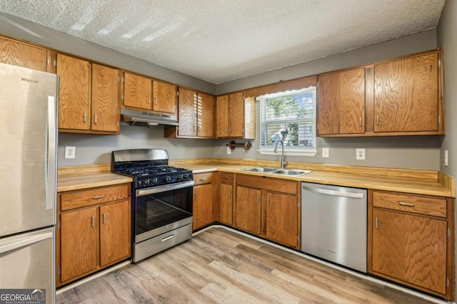 kitchen featuring sink, stainless steel appliances, a textured ceiling, and light hardwood / wood-style floors