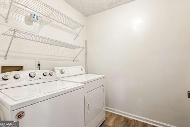 clothes washing area with washer and clothes dryer, dark hardwood / wood-style floors, and a textured ceiling