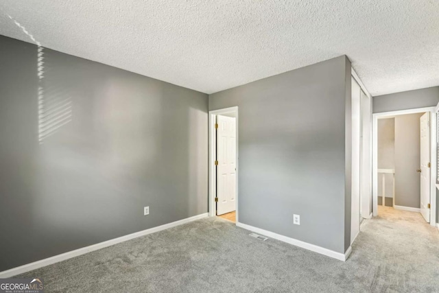 carpeted empty room with a textured ceiling