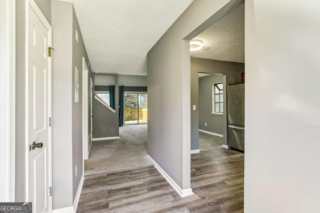 corridor with light hardwood / wood-style floors and a textured ceiling