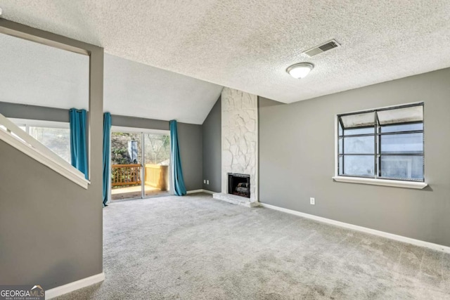 unfurnished living room with a fireplace, a textured ceiling, carpet floors, and lofted ceiling