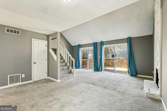 unfurnished living room with a textured ceiling, carpet flooring, and vaulted ceiling