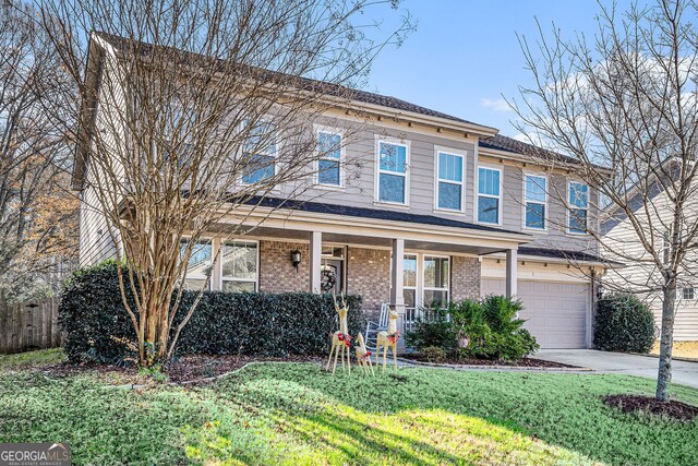 view of property with covered porch, a garage, and a front lawn