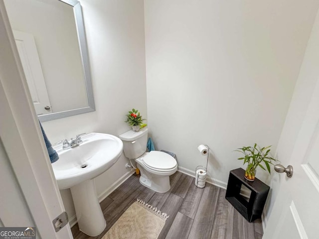 bathroom featuring wood-type flooring, toilet, and sink