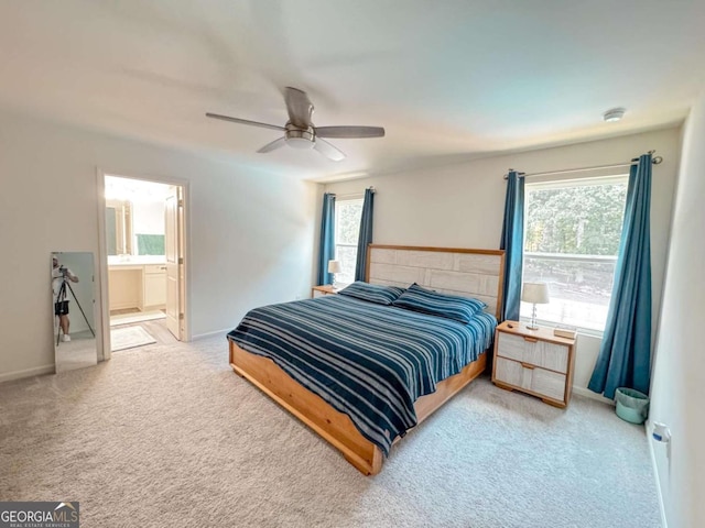 carpeted bedroom featuring ensuite bath, ceiling fan, and multiple windows