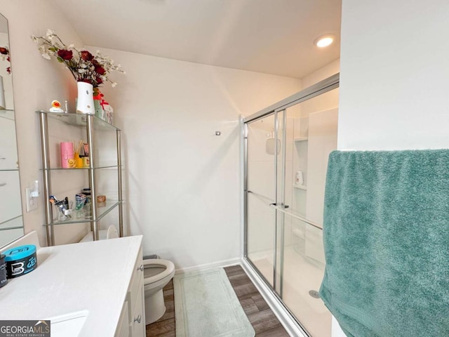 bathroom featuring hardwood / wood-style flooring, vanity, toilet, and a shower with shower door