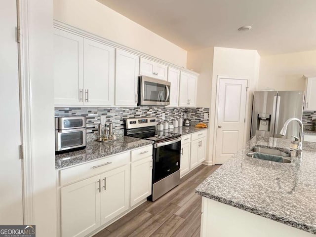 kitchen with white cabinets, appliances with stainless steel finishes, hardwood / wood-style floors, and sink