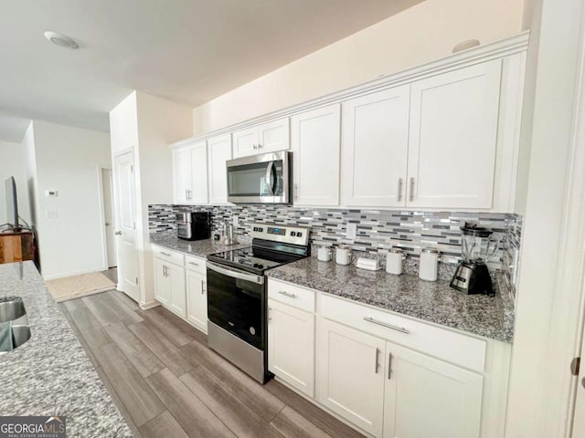 kitchen featuring light stone countertops, white cabinets, light wood-type flooring, and appliances with stainless steel finishes