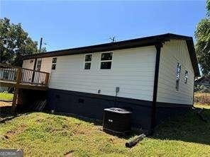 view of home's exterior featuring a deck, a yard, and central AC