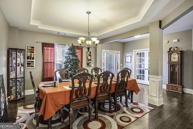 dining room featuring dark hardwood / wood-style floors, a chandelier, and a tray ceiling