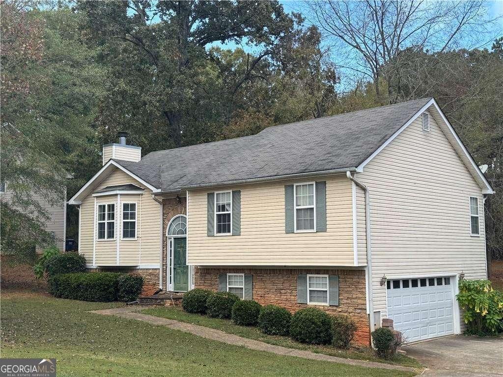 raised ranch featuring a front lawn and a garage