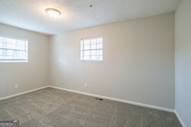 carpeted empty room featuring a textured ceiling