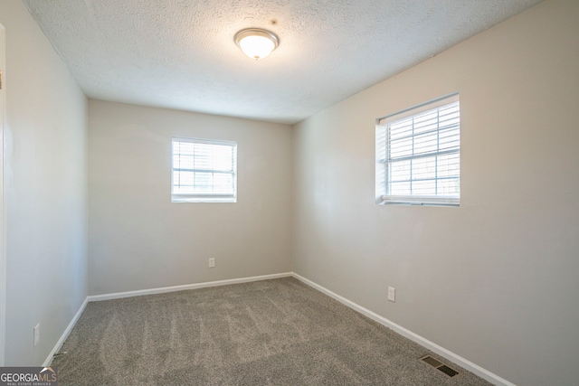 carpeted empty room with a textured ceiling