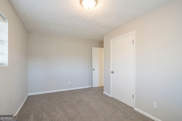 carpeted empty room with a textured ceiling