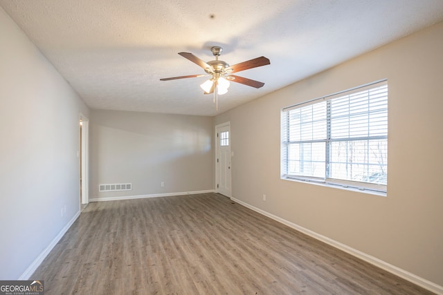 empty room featuring hardwood / wood-style flooring, ceiling fan, and a textured ceiling