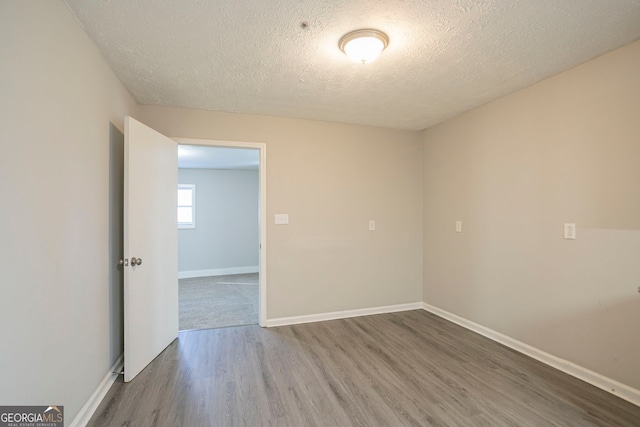 spare room featuring wood-type flooring and a textured ceiling