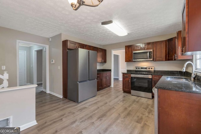 kitchen featuring a textured ceiling, light hardwood / wood-style floors, sink, and appliances with stainless steel finishes