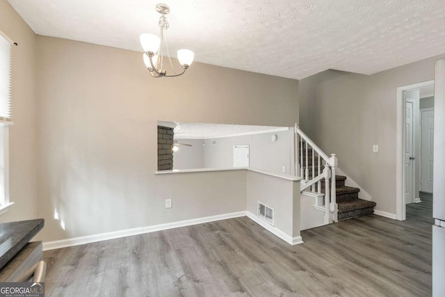 interior space featuring a textured ceiling, hardwood / wood-style flooring, and an inviting chandelier