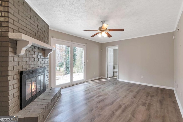 unfurnished living room with crown molding, hardwood / wood-style flooring, ceiling fan, a textured ceiling, and a fireplace