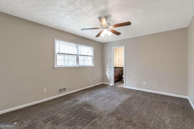 unfurnished bedroom featuring dark colored carpet, a textured ceiling, connected bathroom, and ceiling fan