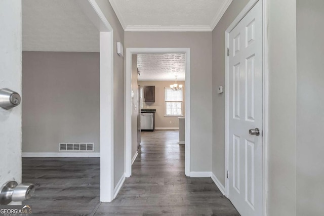 hallway with a textured ceiling, crown molding, dark wood-type flooring, and a chandelier