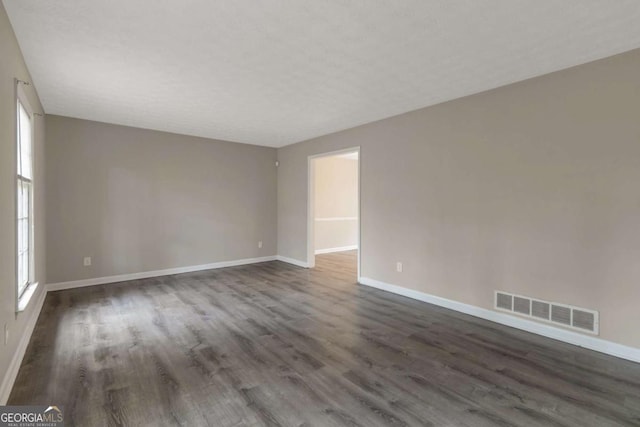 unfurnished room featuring a wealth of natural light and dark hardwood / wood-style floors