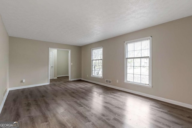 empty room featuring dark wood-type flooring and a textured ceiling