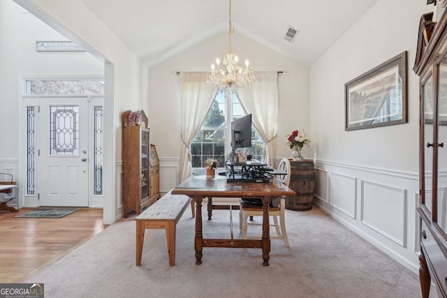 carpeted dining space with vaulted ceiling and a chandelier