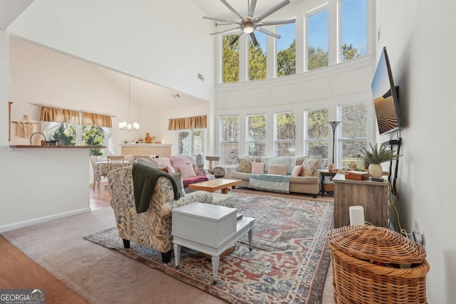 living room with ceiling fan with notable chandelier, a towering ceiling, and hardwood / wood-style flooring